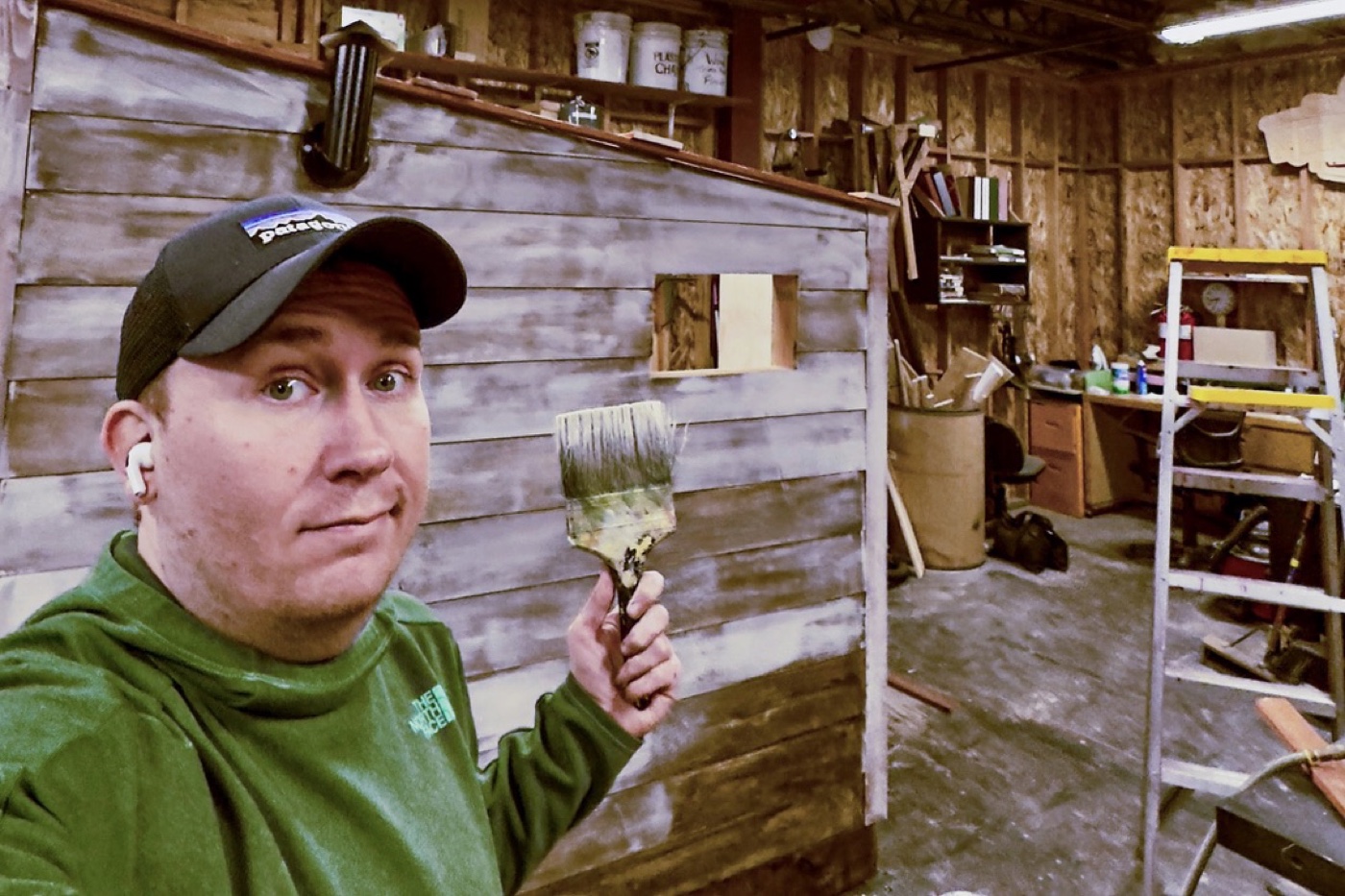 Scenic designer Brandon PT Davis holding a paintbrush while painting scenery in the shop
