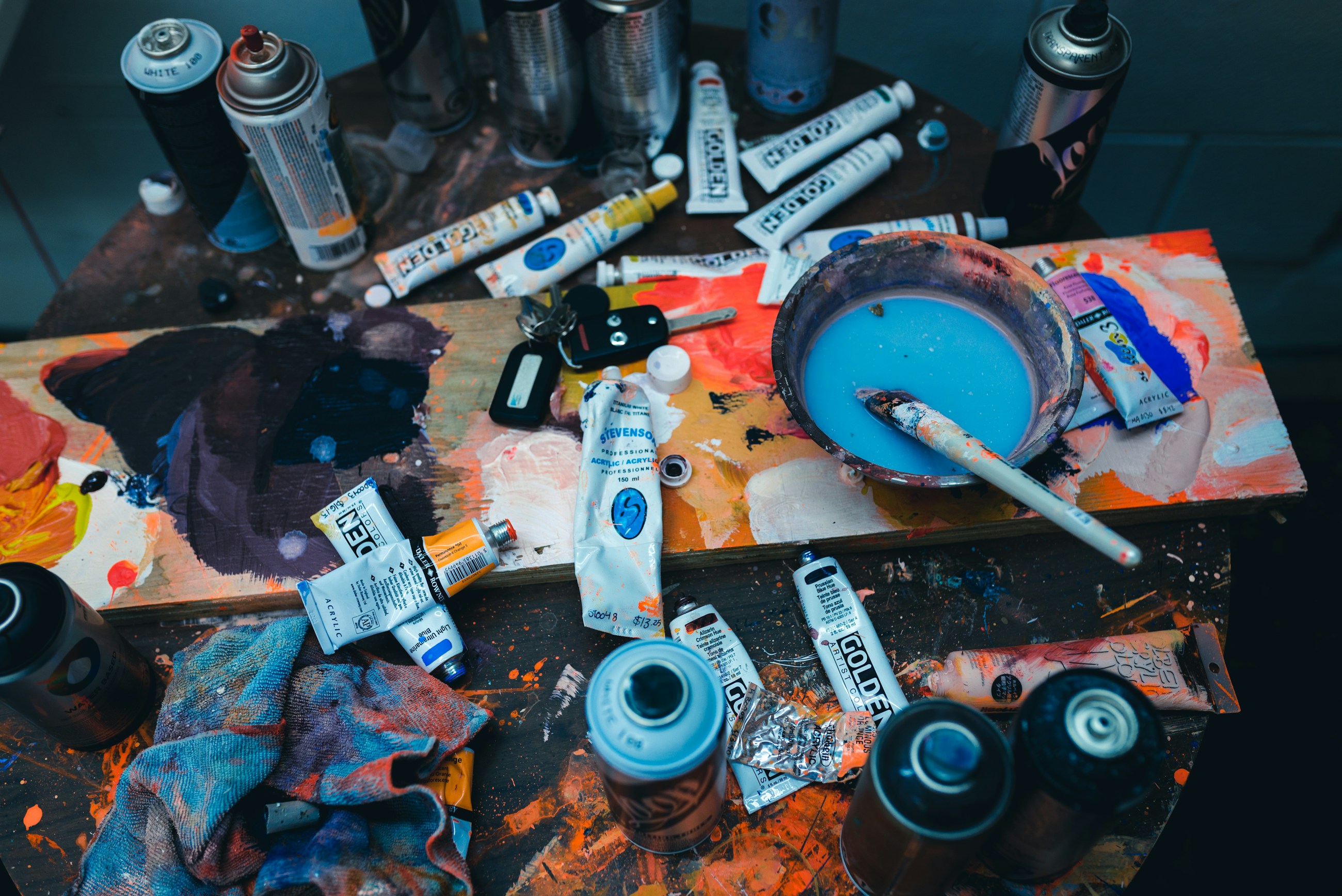 Paint, brushes, and mixing tools spread across a working artist table
